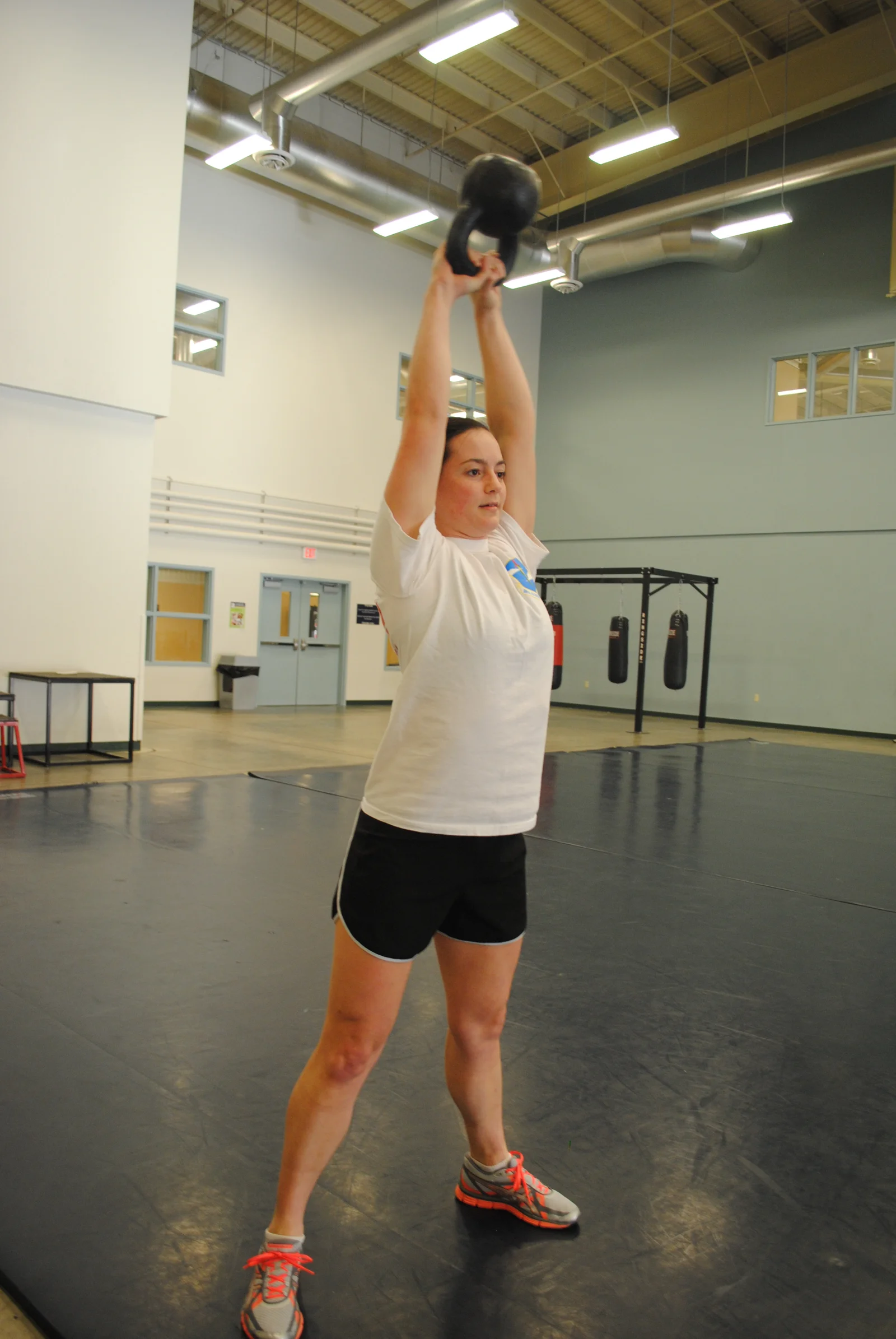 Femme réalisant un exercice de force avec un kettlebell en salle de sport, illustrant l'entraînement en résistance chez la femme