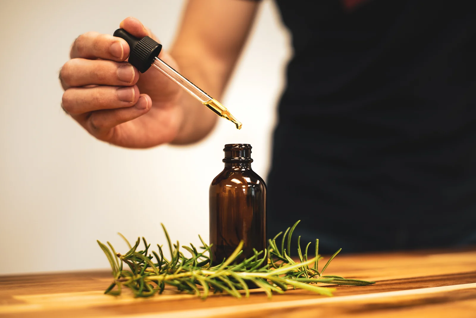 Application d'huile essentielle de romarin depuis un flacon sur les mains